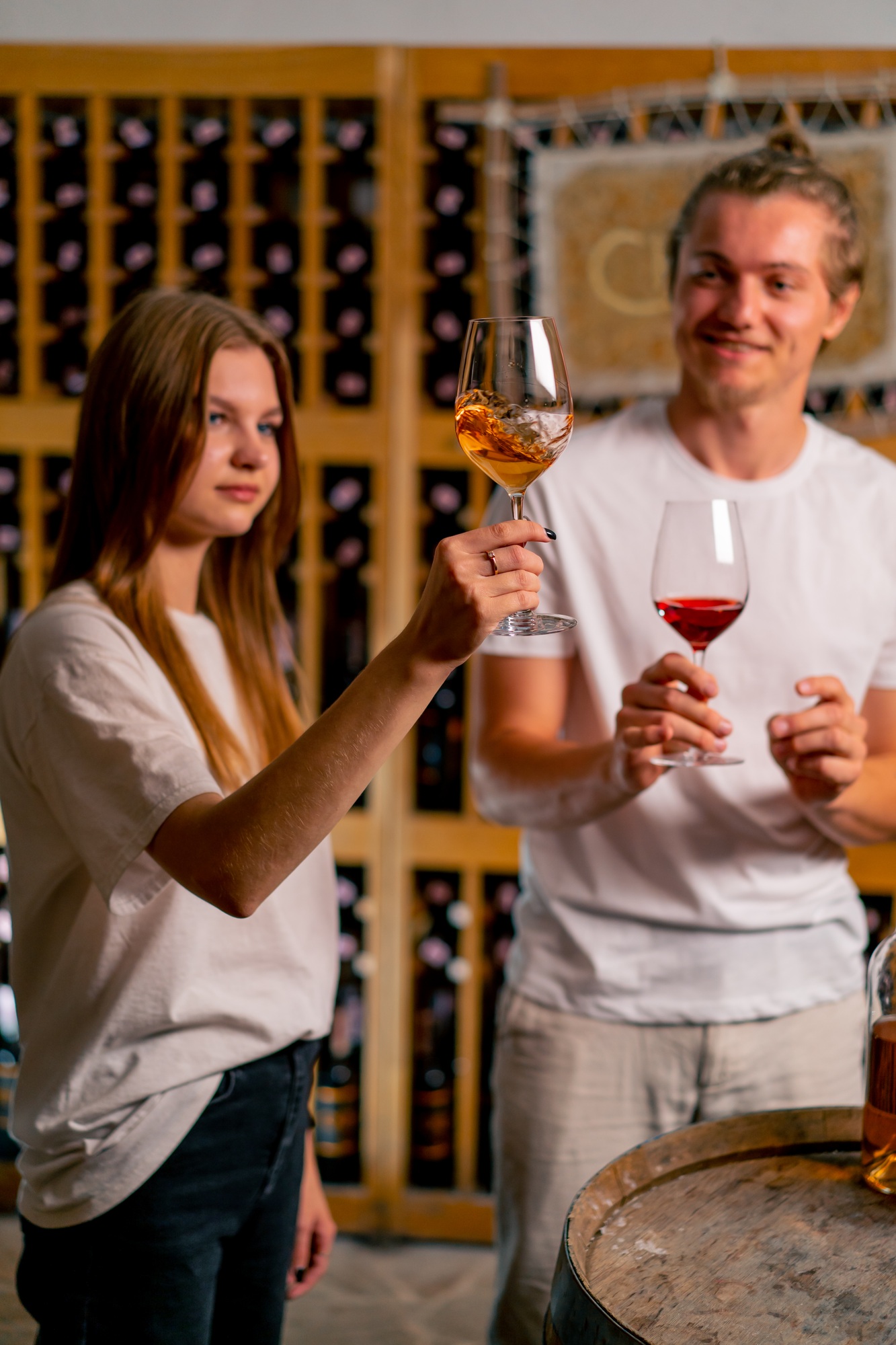 A girl at a wine tasting listens attentively to a male sommelier and tastes wine